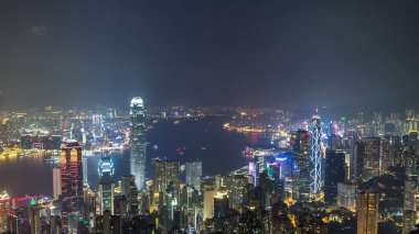 Gece vakti Victoria Limanı ve gökdelenlerin ışıklarıyla aydınlandığı Hong Kong şehrinin gökyüzü gökyüzü gökyüzü gökdelenleri dağın tepesinden görülebiliyor..
