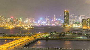 Gündüzden geceye Hong Kong, Kowloon Körfezi 'nden hava görüntüsü gün batımından sonra şehir merkezinde. Aydınlatılmış gökdelenler panoraması