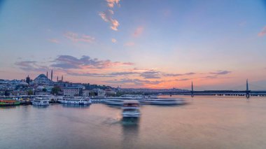 Günbatımı panoramik zaman çizelgesinde İstanbul 'un İstanbul siluetinde, İstanbul Boğazı yakınlarındaki Golden Horn tekne istasyonu yakınlarındaki yolcu feribotları. Arka plandaki cami ve köprü bahar günündeki su yansıması ile