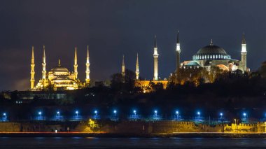 Hagia Sophia and Blue Mosque reflected in Bosphorus water timelapse at night. View from asian shore part of the city near madens tower. Istanbul, Turkey