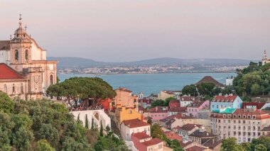 Miradouro da Graca perspektifindeki turistler gün batımında Lizbon 'a bakıyor. Şehrin en iyilerinden biri ve çok popüler. Yeni açılmış füniküler yukarı ve aşağı gidiyor. Portekiz