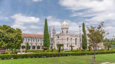 Mosteiro dos Jeronimos ve bahçede çimenliği olan yeşil ağaçlar, Lizbon, Portekiz 'in Belem bölgesinin zaman diliminde yer almaktadır. Manueline tarzı (Portekizce geç Gotik). Mavi gökyüzünde bulutlar