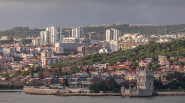 Lizbon, Portekiz 'deki Belem Kulesi' nin hava zaman çizelgesi, Tagus Nehri 'nin tarihi simgesi. Akşamları deniz manzarası, insanlar arka planda bir inşaat alanından vincin etrafında geziniyor.