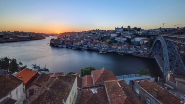 Panorama of old city Porto at river Duoro, with Port transporting boats at sunset timelapse with the Dom Luiz bridge, Oporto, Portugal