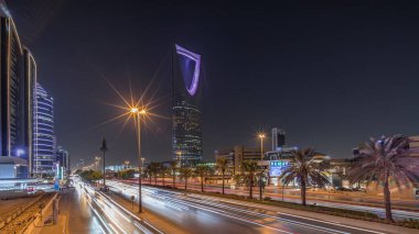 Riyad karayolu trafiğinin yer aldığı panoramik gece zaman çizelgesi, Krallık Kulesi Suudi Arabistan 'ın başkentinin en yüksek gökdeleni ve simgesi. Aydınlatılmış modern binalar canlı sahnenin etrafını sarar.
