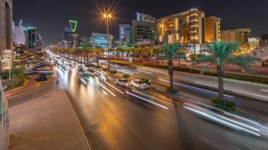 Riyad, Suudi Arabistan 'ın şehir havası gece zaman çizelgesi. Aydınlatılmış ünlü kuleler, gökdelenler, Kral Fahd Yolu ve yoğun trafik yer alıyor. Palmiyeler ve sokak lambaları şehrin içinden geçen ana otoyol boyunca uzanır.