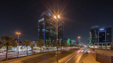 Suudi Arabistan, Riyad 'ın şehir manzarası gece zaman çizelgesi. Işıklı kulelerin, gökdelenlerin, King Fahd Yolu 'nun ve yoğun trafiğin panoramik görüntüsü. Palmiyeler ve sokak lambaları şehrin içinden geçen ana otoyolda.