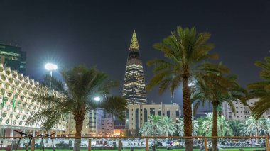 Kral Fahad Ulusal Kütüphanesi 'nin avuçlar ve parlayan kuleyle aydınlatılmış cephesinin perspektif gece zaman çizelgesi. Suudi Arabistan 'ın Riyad şehrinde insanlar canlı meydanda yürüyorlar..