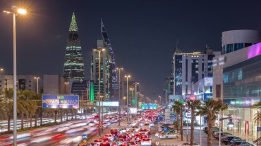 Riyad, Suudi Arabistan 'ın şehirsel gece zaman çizelgesinde aydınlık kuleler, gökdelenler, Kral Fahd Yolu ve yoğun trafik yer alıyor. Palmiyeler ve sokak lambaları şehrin içinden geçen ana otoyol boyunca uzanır..