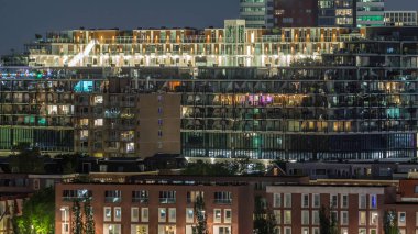 Geceleri Katendrecht Yarımadası 'nın ve Rotterdam, Hollanda' daki Maashaven Limanı 'nın uçuş zamanı. Aydınlatılmış şehir silüeti, parlayan modern binalar ve geleneksel Hollanda rıhtım evleri