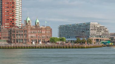 Rotterdam şehir merkezindeki Otel New York 'un tarihi cephesine sahip modern binaların zaman çizelgesi. Eski Hollanda-Amerika Hat Karargahı. Tekneler geçerken insanlar rıhtımda dinleniyor. Simgesel mimari
