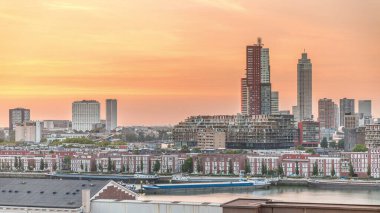 Günbatımında Rotterdam şehir merkezindeki modern binaların hava zaman çizelgesi, Hollanda. Finans bölgesinde kuleler ve gökdelenler, turuncu gökyüzü ile eski fabrika canlı bir ufuk çizgisi oluşturur