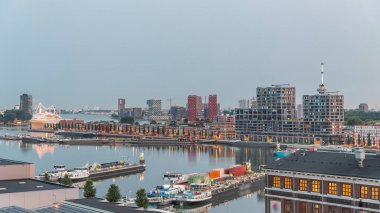 Güneş doğmadan önce Maashaven 'daki kuleler üzerindeki hava manzarası demirli gemilerle, Katendrecht ve Maas Nehri' yle, Rotterdam 'la geçiş zamanlarını gösteriyor. Aydınlatılmış fabrika ofis ve olay alanına dönüştürüldü