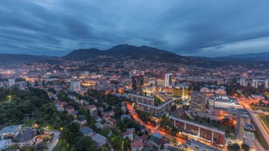 Saraybosna 'nın güney kesiminin gündüz ve gece hava görüntüsü. Gökdelenleri ve dağları olan gökdelenler. Gün batımından sonraki en yüksek kuleden. Bosna-Hersek ve Güneydoğu Avrupa.