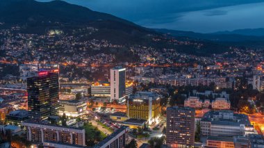 Saraybosna 'nın güney kesiminin gündüz ve gece hava görüntüsü. Gökdelenleri ve dağları olan gökdelenler. Gün batımından sonraki en yüksek kuleden. Bosna-Hersek ve Güneydoğu Avrupa.