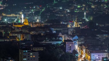 Saraybosna 'nın tarihi kısmının hava manzaralı gece zaman dilimi. Aydınlatılmış gökdelenleri ve yüksek kule manzaralı dağları olan bir gökyüzü. Bosna-Hersek ve Güneydoğu Avrupa.