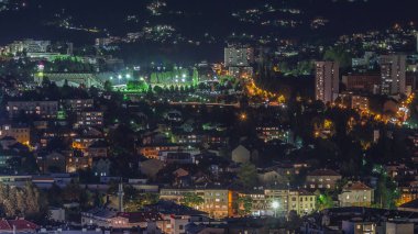 Saraybosna 'daki Eski Yahudi mezarlığından aydınlatılmış evler ve dağlarla dolu bir panorama. Trafikli Skyline. Bosna-Hersek