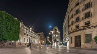 Avenida de la Constitucion gece vakti Seville, İspanya 'da aşırı hız. Iconic Adriatica binası akşam parlıyor. Modern sokak lambaları, yayalar ve şehir atmosferine sahip tarihi mimari