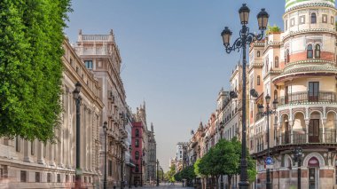 Avda boyunca yürüyen yayalar. De la Constitucion, Seville, İspanya 'nın Casco Antiguo bölgesindeki ana cadde. Edificio de la Adriatica yakınlarındaki zaman dilimi, tarihi binalar ve geçen tramvaylar