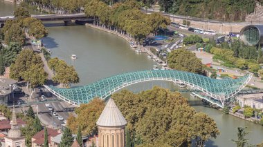 Rike Park 'ı Gürcistan' ın başkenti Tiflis 'e bağlayan, Kura Nehri üzerinde yay şeklinde bir çelik ve cam köprü olan Barış Köprüsü' nden Timelapse. Bir bakış açısından hava görüntüsü