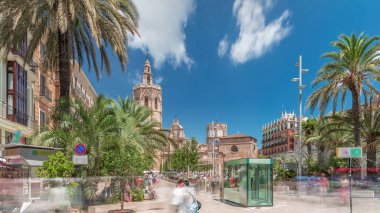 Valencia, İspanya 'da Plaza de la Reina' nın panoramik zaman atlaması. Tarihi bir kilise kulesi, hareketli kafeler ve sıcak Akdeniz semaları altında palmiyeleri olan merkezi bir çeşme..