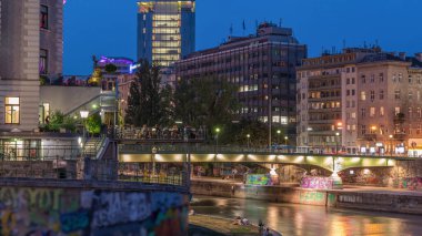 Viyana 'da Tuna kanalı ile Viyana şehir manzarası Viyana' da günden geceye geçiş zamanı. Avusturya. Yeşil ağaçlı binalar ve trafiği olan köprüler