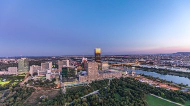 Donau City gökdelenleri, tarihi binalar ve Avusturya 'da gece gündüz nehir kenarındaki gezinti güvertesi ile Viyana üzerinde havadan panoramik bir manzara. Akşam üstü Tuna Kulesi 'nden gün batımından sonra gökyüzü