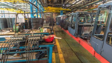 Konveyör montajı, traktörün gövdesini büyük endüstriyel fabrika zaman diliminde sahneleyecek. Kabin montajı, kurulum parçaları özel bir masada.