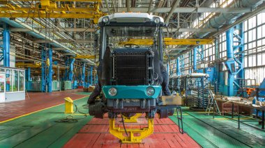 Konveyör montajı, traktörün gövdesini büyük endüstriyel fabrika zaman diliminde sahneleyecek. Çerçeve montajı, radyatör ve kabin kurulumu ve diğer parçaları olan motor.