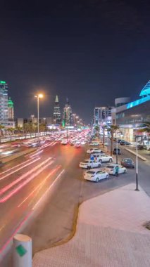 Riyad, Suudi Arabistan 'ın şehirsel gece zaman çizelgesinde aydınlık kuleler, gökdelenler, Kral Fahd Yolu ve yoğun trafik yer alıyor. Palmiyeler ve sokak lambaları alışveriş merkezinin yakınındaki ana otoyolda.