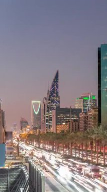 Suudi Arabistan, Riyad 'daki Kral Fahd Yolu' nun hava-gece zaman çizelgesi. Aydınlatılmış Riyad Ulusal Kütüphanesi yakınlarında modern kuleler ve gökdelenlerle çevrili araçlar ve taksilerle dolu.