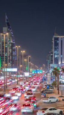 Riyad, Suudi Arabistan 'ın şehirsel gece zaman çizelgesinde aydınlık kuleler, gökdelenler, Kral Fahd Yolu ve yoğun trafik yer alıyor. Palmiyeler ve sokak lambaları şehrin içinden geçen ana otoyol boyunca uzanır..