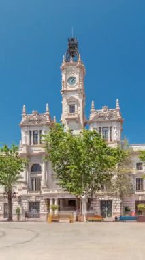 Valencia Belediye Binası Ajuntament de Valencia zaman atlaması Plaza de Ayuntamiento 'da. Mavi bulutlu gökyüzünün altında saat kulesi olan tarihi bir bina. İspanya 'nın ana meydanında gezinen insanlar