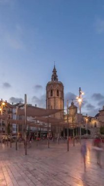 İspanya, Valencia 'daki Plaza de la Reina' da panoramik günden geceye geçiş süreleri aşırı hızlanıyor. Tarihi bir kilise kulesi, hareketli kafeleri ve akşam gökyüzünün altında merkezi bir çeşmesi olan canlı bir meydan..