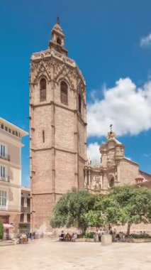 Valencia, İspanya 'da Plaza de la Reina' nın panoramik zaman atlaması. Tarihi bir kilise kulesi, hareketli kafeler ve sıcak Akdeniz mavi bulutlu gökyüzünün altında merkezi bir çeşme ile dolu canlı bir meydan..
