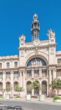 Panorama, Valensiya 'daki tarihi Postane Palau de les Comunicacions' ı gösteriyor. Şehir Meydanı Plaza del Ayuntamiento 'da. Süslü cephe, trafik ve İspanya şehir merkezinde mavi bir gökyüzü..