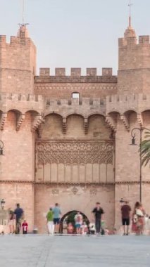 Serrans Kuleleri Torres de Serranos zamanapse Valencia, İspanya 'da. Şehrin antik duvarlarından gelen büyük bir ortaçağ kapısı. İnsanlar gün batımından önce tarihi bir dönüm noktasında köprüde yürüyorlar.