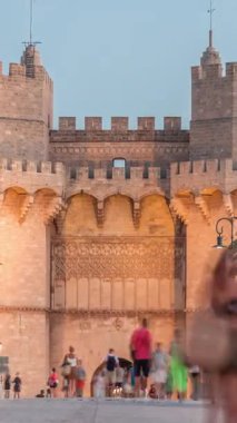 Serrans Kuleleri Torres de Serranos günden geceye Valencia, İspanya 'daki geçiş zamanı. Şehrin antik duvarlarından gelen büyük bir ortaçağ kapısı. İnsanlar tarihi bir dönüm noktasının yakınındaki bir köprüde yürüyorlar.