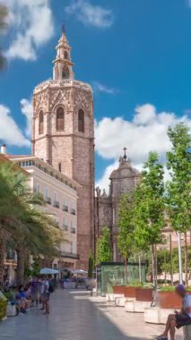 Valencia, İspanya 'daki Plaza de la Reina' nın panoramik zaman çizelgesi. Tarihi bir kilise kulesi, hareketli kafeler ve sıcak Akdeniz bulutlu gökyüzünün altında merkezi bir çeşme..