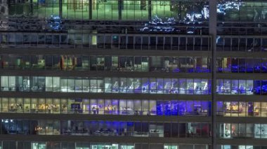 İş kulesi binasının gece ön cephesinde ışık zamanlaması olan bir sürü pencere var. Her pencerede hayat var. Bir ofis gökdeleninin cam cephesinin havadan görünüşü.