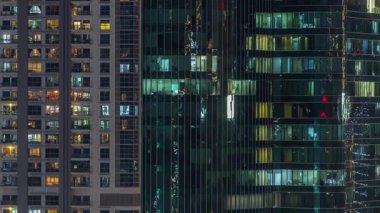 Ofis ve konutların pencereleri gece vakti aydınlatılıyor. Cam mimari, şirket binası, parlayan ışıklar.