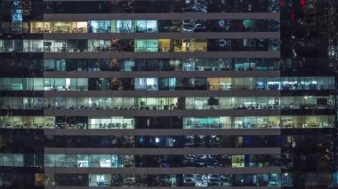 Ofis binalarının camları gece saatlerinde aydınlatılıyor. Cam mimari, şirket binası, parlayan ışıklar.