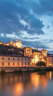 Aziz John 'un Vaftizci Katedrali ve Lyon' daki Notre-Dame de Fourviere Bazilikası 'nın zaman çizelgesi, günden geceye değişiyor. Yansıtılmış rıhtım ve nehirde yansıyan binalar. Fransa