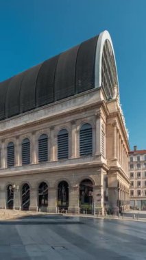 Modern cam kubbe ile birleştirilmiş neoklasik mimari içeren Lyons opera binasının hiperlapesi. Mavi gökyüzünün altında heykelleri olan tarihi ve turistik bir yer. Yan görünüm zaman dilimi