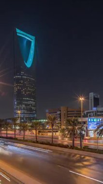 Riyad karayolu trafiğinin yer aldığı panoramik gece zaman çizelgesi, Krallık Kulesi Suudi Arabistan 'ın başkentinin en yüksek gökdeleni ve simgesi. Aydınlatılmış modern binalar canlı sahnenin etrafını sarar.