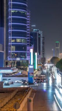 Suudi Arabistan 'ın Riyad kentindeki ikonik bükümlü gökdeleniyle King Fahd Yolu' ndaki yoğun karayolu trafiğinin hava takvimi görüntüsü. Dünyanın en yüksek sekizinci büküm kulesi. Aydınlatılmış sokaklar ve ağaçlar