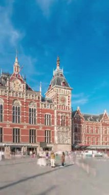 Amsterdam Merkez Tren İstasyonu 'nda tarihi bir girişi olan hiperlapse. Bir sürü yolcu zaman içinde girip çıkıyor. Mavi gökyüzündeki bulutlar. Amsterdam, Hollanda