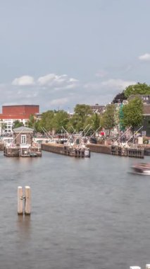 Amstel Nehri 'ndeki Amstel kilitlerinden geçen teknelerin panoramik görüntüsü. Opera binası ve Zuiderkerk kulesi arka planda görünüyor. Bulutlar gökyüzünü dolduruyor. Amsterdam, Hollanda