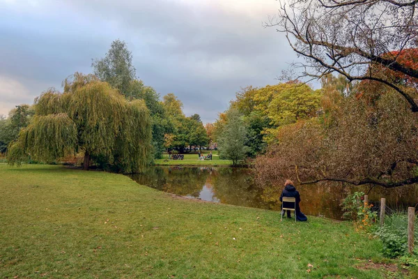 荷兰阿姆斯特丹萨法蒂公园池塘边的椅子上坐着一位女士 — 图库照片
