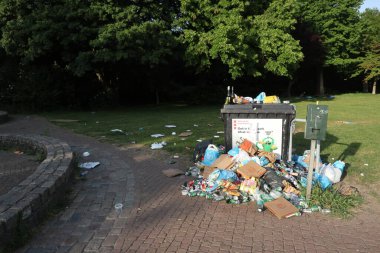 Parktaki çöp tenekesinin yanındaki çöplükte eğlence sektörü çalışanları var.